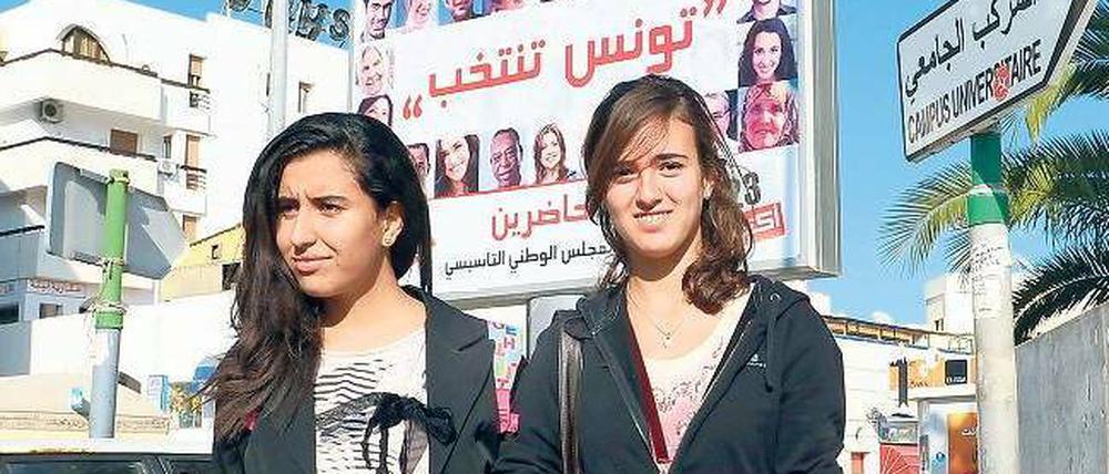 Demokratische Vorfreude. Zwei Studentinnen in Tunis, wo die Parteien vor der Wahl am Sonntag eifrig plakatierten. Insgesamt 90 Listen bewerben sich um Sitze in der verfassunggebenden Versammlung des Landes. 