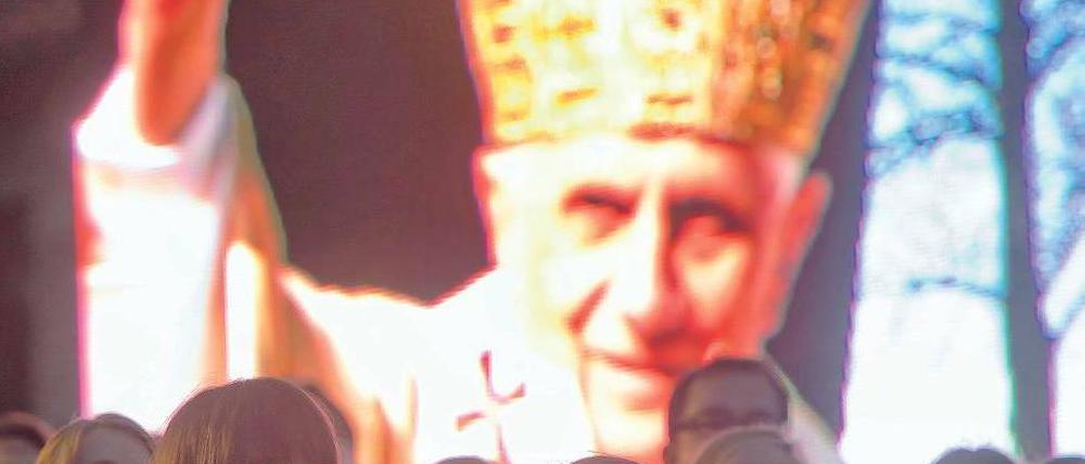 Singen und Warten. In Berlin und anderen Diözesen laufen die Vorbereitungen für den Besuch Benedikts XVI. – wie hier auf Burg Scharfenstein in Thüringen. Dort sang der Jugendchor vor einem Bild des Papstes während einer ökumenischen Lichterfeier. Foto: dapd