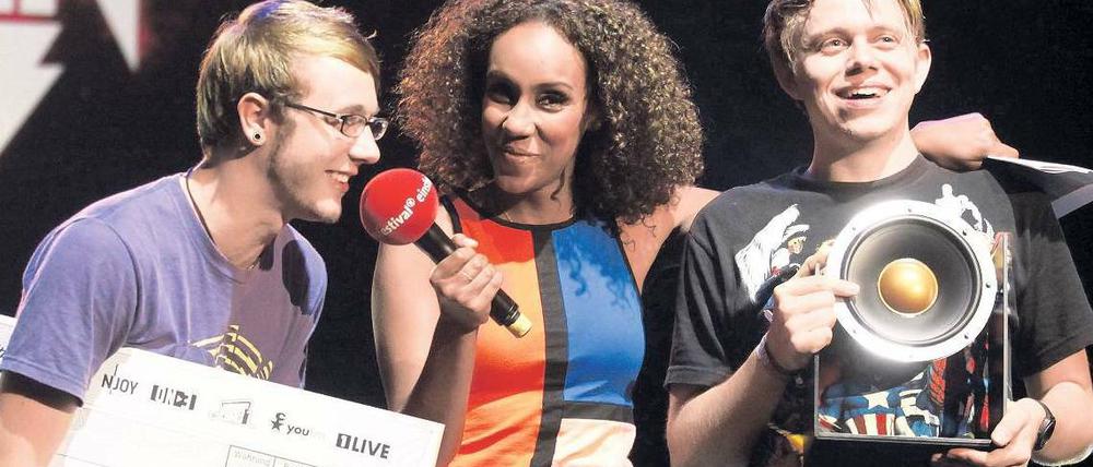 Hannes Naumann und Maik Biermann alias Captain Capa bei der Preisverleihung mit Moderatorin Hadnet Tesfai. Foto: Roland Owsnitzki