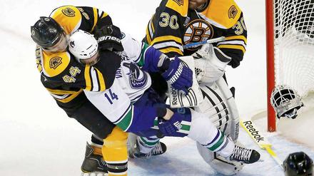 Helm ab zum Ringkampf: Dennis Seidenberg im Clinch mit Alex Burrows (Vancouver), der Bostons Torwart Tim Thomas zuvor die Kopfbedeckung heruntergeschlagen hat.