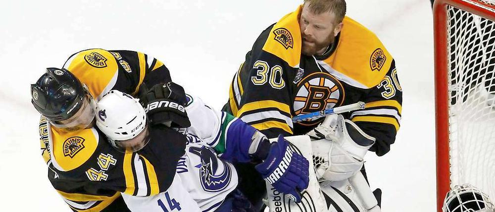 Helm ab zum Ringkampf: Dennis Seidenberg im Clinch mit Alex Burrows (Vancouver), der Bostons Torwart Tim Thomas zuvor die Kopfbedeckung heruntergeschlagen hat.