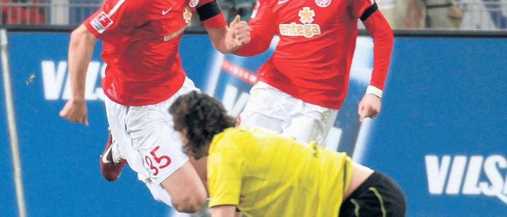 Hab ich was verpasst? Dortmunds Neven Subotic lag nach einem Schuss in den Unterleib noch am Boden, als der Mainzer Petar Sliskovic (l.) das 1:1 erzielte. André Schürrle (r.) jubelt über den Ausgleich. Foto: dapd