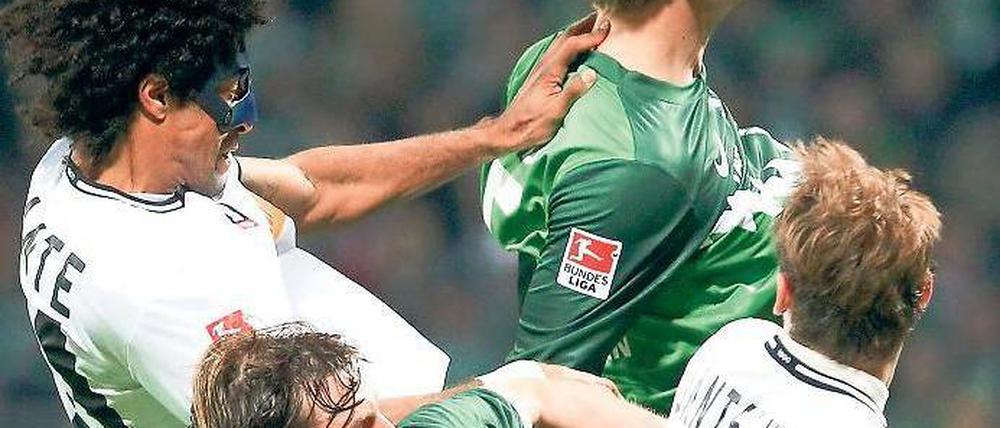 Ästhetik des Abstiegskampfs. Vier Mann, zwei Bremer, zwei Gladbacher, streiten um einen Ball. 