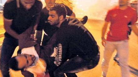 Szene eines Aufstands. Demonstranten tragen am Freitag einen Verletzten vom Lulu-Platz in Manama, der bahrainischen Hauptstadt. Am Samstag herrschte zunächst Ruhe. Foto: dpa