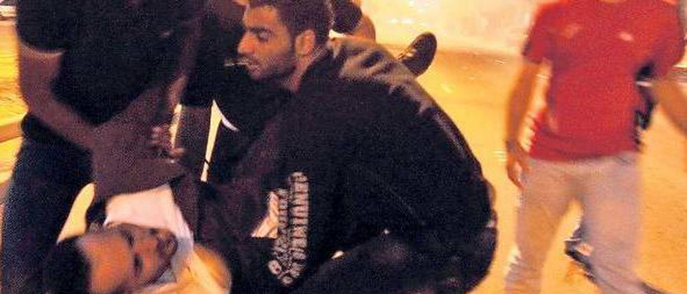 Szene eines Aufstands. Demonstranten tragen am Freitag einen Verletzten vom Lulu-Platz in Manama, der bahrainischen Hauptstadt. Am Samstag herrschte zunächst Ruhe. Foto: dpa