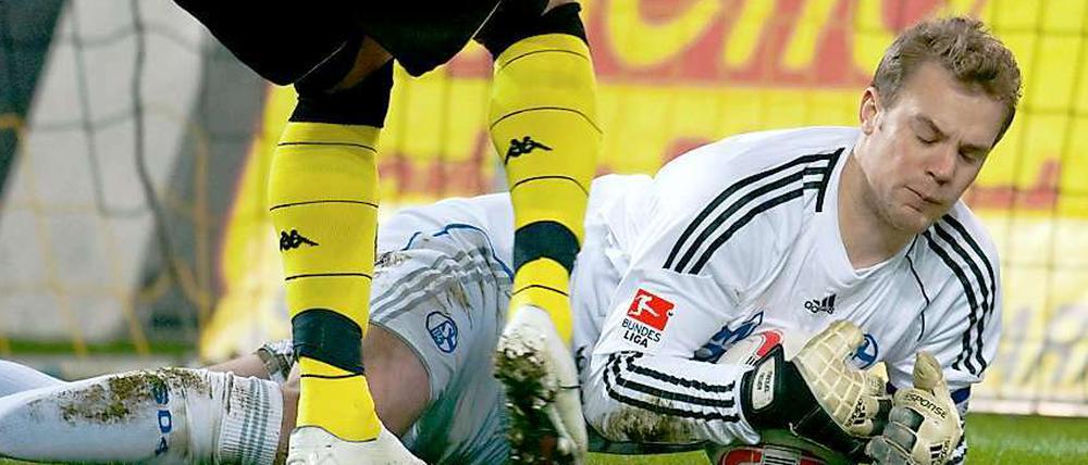 Schalkes Torhüter Manuel Neuer sichert den Ball vor Dortmunds heranstürmendem Lucas Barrios.
