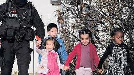 Ein Polizist führt nach dem Ende der Geiselnahme Kinder ins Freie. 