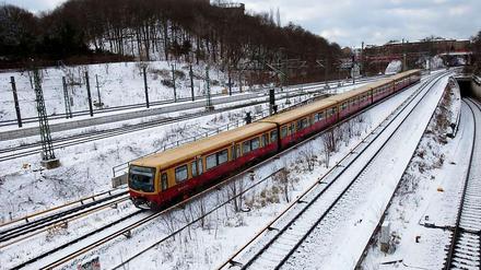 Eine S-Bahn fährt über verschneite Gleise.