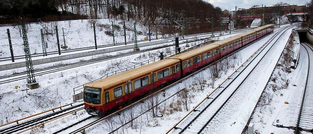 Eine S-Bahn fährt über verschneite Gleise.