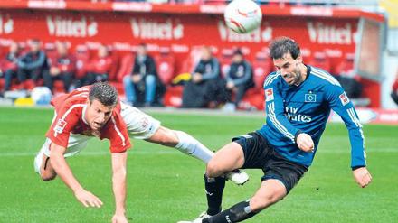 Zweiter Sieger. Marco Caligiuri (l.) kommt gegen HSV-Stürmer Ruud van Nistelrooy zu spät, Mainz fiel auf Rang zwei zurück. Foto: dapd