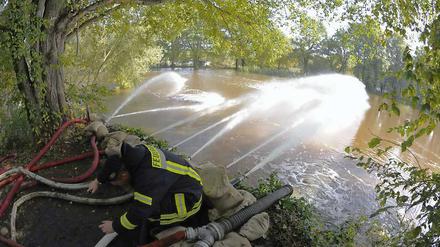 Feuerwehrleute pumpen Wasser von einer überschwemmten Fläche in die Schwarze Elster.