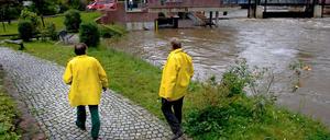 Zwei Deichläufer, die bei Hochwasser den Zustand der Deiche überwachen, gehen am Stadtmühlenwehr in Spremberg an der Spree entlang. 