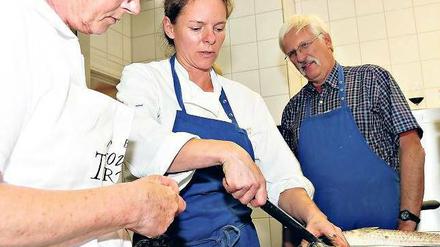 Die Küchenchefin lehrt, große Fische zu zerlegen.