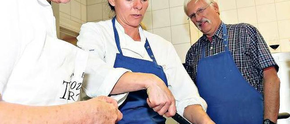 Die Küchenchefin lehrt, große Fische zu zerlegen.