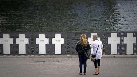 Touristen stehen im Regierungsviertel in Berlin vor Kreuzen zum Gedenken an Maueropfer. Der Bau der Berliner Mauer jährt sich am Freitag zum 49. Mal.