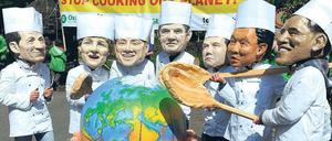 Petersberger Klimadialog. Demonstranten mit Masken der mächtigsten Politiker stehen vor einem Kochtopf, in dem symbolisch das Klima der Erde erhöht wird. Foto: dpa