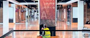 Fertig zum Putzen. Ein Arbeiter im Hauptterminal des BER reinigt ein Schild, das künftig den Weg zu den Abflugbereichen weisen soll. Der unvollendete Hauptstadtflughafen wird immer teurer.
