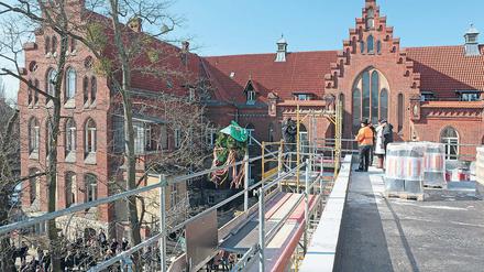 Richtkranz mit OP-Kittel. Das denkmalgeschützte Ensemble des Oberlinhauses an der Rudolf-Breitscheid-Straße wird durch einen Kubus – hier die Sicht von dessen Dach – für zwei neue Operationssäle ergänzt. Der Neubau soll Ende 2018 fertig sein.