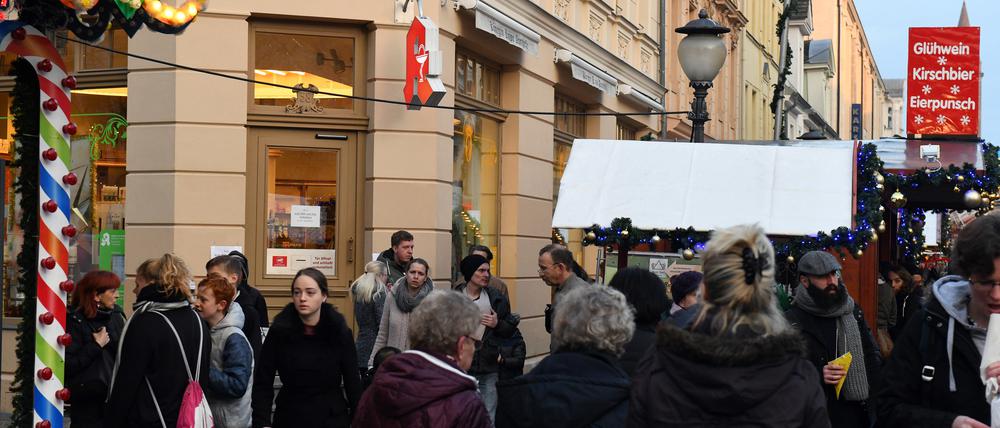 Passanten stehen am Samstag in Potsdam auf dem Weihnachtsmarkt an der Apotheke, in der am Vortag ein verdächtiges Paket abgegeben worden war. Darin befanden sich Hunderte Nägel und ein sogenannter Polenböller.