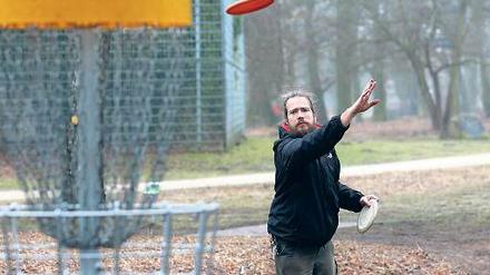 Präzisionsarbeit. Discgolfer werfen ihre Frisbees in Metallkörbe.