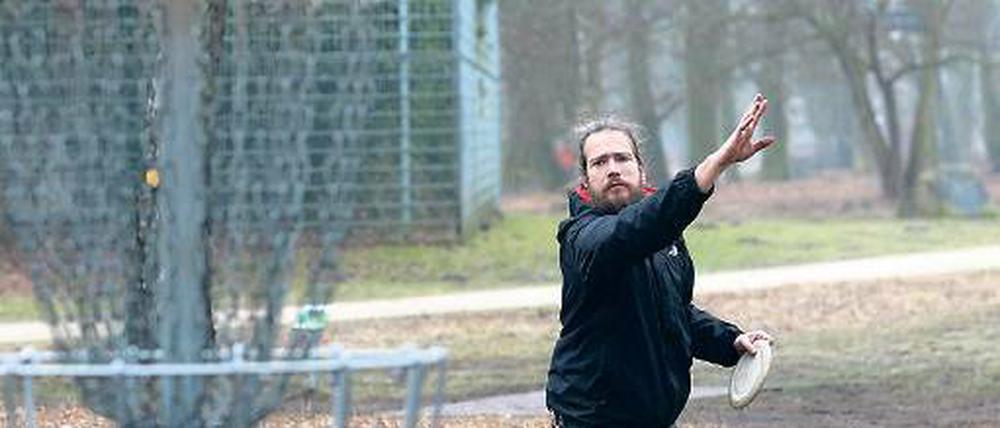 Präzisionsarbeit. Discgolfer werfen ihre Frisbees in Metallkörbe.