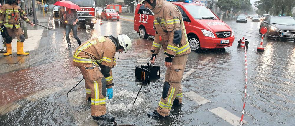 Einsatz am Gullydeckel. Feuerwehrmänner in der überfluteten West-City.
