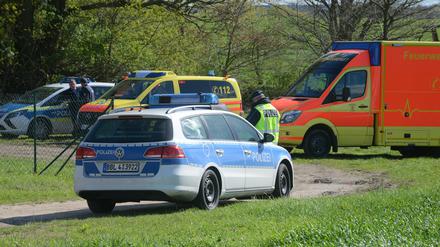 Polizei- und Rettungsfahrzeuge am Rand einer Straße bei Priort (Havelland). Dort sind am Montag zwei männliche Leichen in einem Auto entdeckt worden.