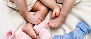 Babys liegen auf einem Bett.