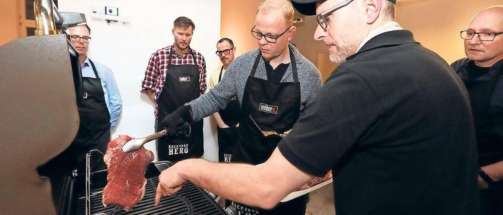 Meat and Greet. Die Teilnehmer der Weber-Grillakademie in Potsdam sind hochkonzentriert, als das teure Steak auf den Rost kommt. Experte und Grillmeister Thomas Streit-Rodriguez (r.) zeigt, wo genau es platziert werden soll. Auch Pizza kann man im Grill backen und Fischspieße sowieso.
