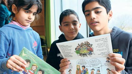 Bereits angekommen. Die Geschwister Maya, Zaid und Zuher (v.l.) der aus Syrien geflüchteten Familie Al Monajjed mit der neuen Broschüre.