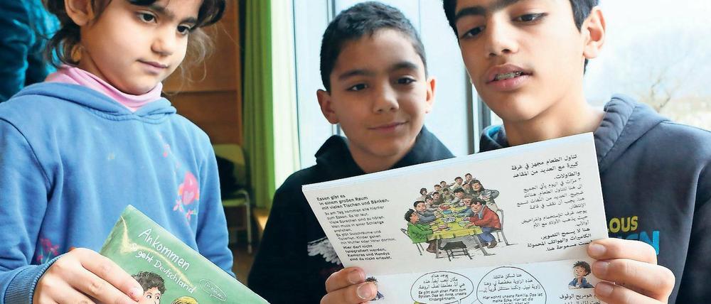 Bereits angekommen. Die Geschwister Maya, Zaid und Zuher (v.l.) der aus Syrien geflüchteten Familie Al Monajjed mit der neuen Broschüre.