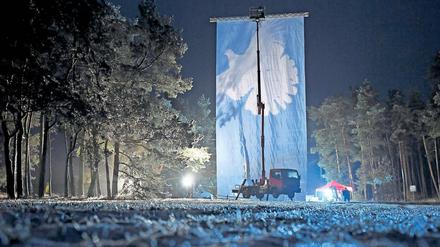 Linke allein im Wald. Mit einem Banner protestierte die Linke am Montagabend vor dem Truppenübungsplatz Lehnin. Anlass war ein angekündigter Zwischenstopp eines Materialtransports der US-Armee nach Polen, der sich allerdings verzögerte.