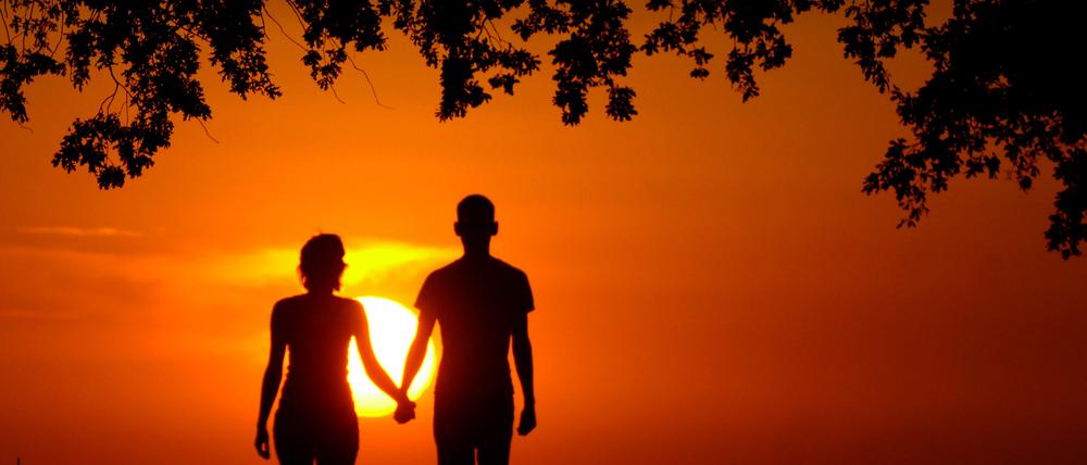 Ein junges Liebespaar Hand in Hand nahe dem brandenburgischen Müncheberg im Sonnenuntergang.
