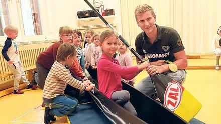 Im Boot des Olympiahelden. Die Kinder aus der Kita „Zauberstein“ – wie hier die fünfjährige Lisa – konnten sich ins Renngefährt von Jan Vandrey knien und auch sein Paddel sowie die Rio-Medaille in die Hände nehmen.