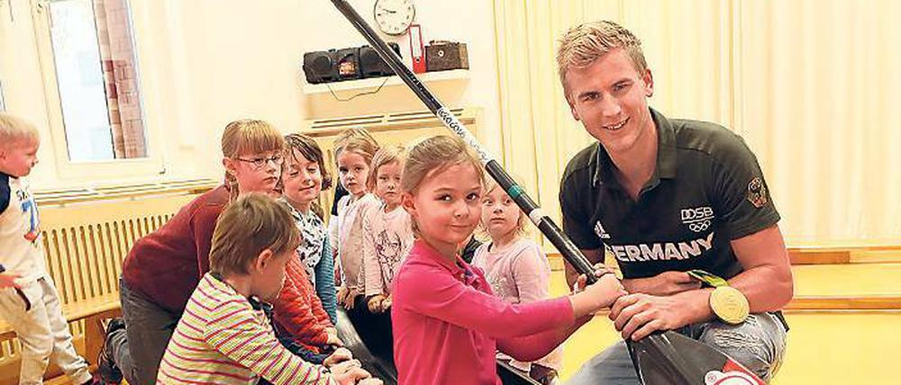 Im Boot des Olympiahelden. Die Kinder aus der Kita „Zauberstein“ – wie hier die fünfjährige Lisa – konnten sich ins Renngefährt von Jan Vandrey knien und auch sein Paddel sowie die Rio-Medaille in die Hände nehmen.