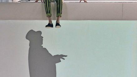 Andere Ebene. Der kluge Doktor (Julian Mehne) inspiziert den scheinbar glücklichen Kaufmann (Peter Wagner), der als Schattenfigur agiert.