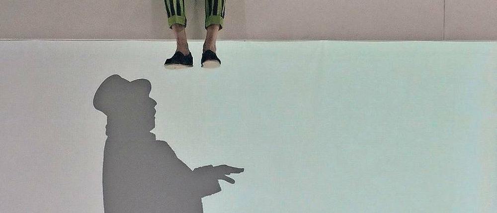 Andere Ebene. Der kluge Doktor (Julian Mehne) inspiziert den scheinbar glücklichen Kaufmann (Peter Wagner), der als Schattenfigur agiert.