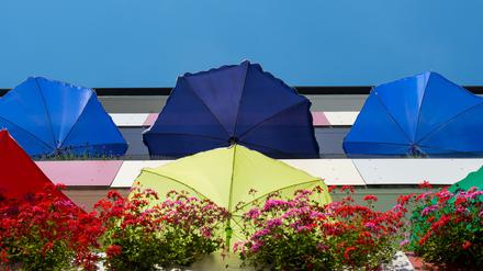 Bunte Sonnenschirme leuchten in der Mittagssonne auf Balkons einen Mehrfamilienhauses in Frankfurt (Oder). Foto: Patrick Pleul/dpa.
