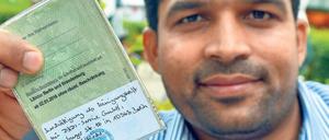 Mit Stolz. Aziz Tariq aus Pakistan mit seiner Arbeitserlaubnis. Er will zeigen, dass er arbeiten kann und will.
