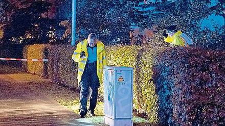 Nach dem Schuss. Polizisten sichern den Tatort im Regen. 
