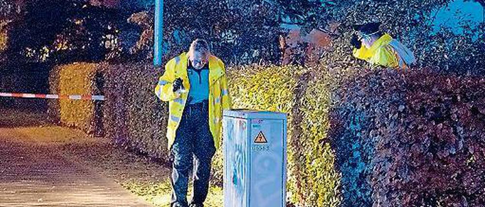 Nach dem Schuss. Polizisten sichern den Tatort im Regen.