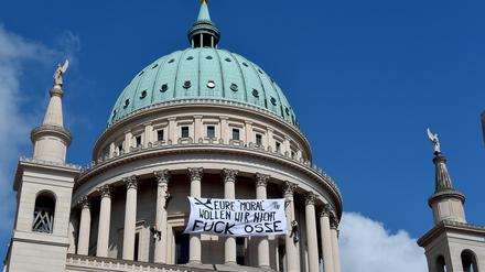 Protest gegen das geplante OSZE-Treffen in Potsdam. Aktivisten hängen ein Transparent mit der Aufschrift "Eure Moral wollen wir hier nicht", an die Nikolaikirche.