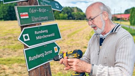Immer am Bohren. Wanderwegewart Horst Jäkel beim Befestigen eines Schildes in Pusack an der Neiße.