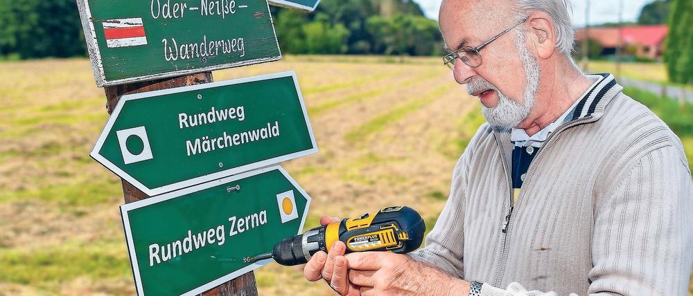 Immer am Bohren. Wanderwegewart Horst Jäkel beim Befestigen eines Schildes in Pusack an der Neiße.