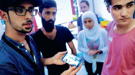 Was denken Neuberliner – etwa über Demokratie, Religion, Juden und Homosexuelle? Klar ist: Fast alle wollen sich hier integrieren. Diese syrischen Flüchtlinge, die vom Verein „Moabit hilft“ betreut werden, verfolgen gerade die Nachrichten aus ihrer alten Heimat auf einem Smartphone.