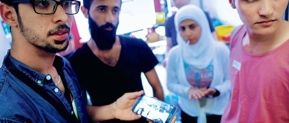 Was denken Neuberliner – etwa über Demokratie, Religion, Juden und Homosexuelle? Klar ist: Fast alle wollen sich hier integrieren. Diese syrischen Flüchtlinge, die vom Verein „Moabit hilft“ betreut werden, verfolgen gerade die Nachrichten aus ihrer alten Heimat auf einem Smartphone.