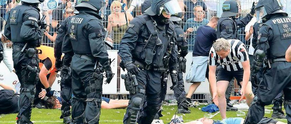 Im Einsatz. Die Polizei und ein Fan, der einem Verletzten helfen will.