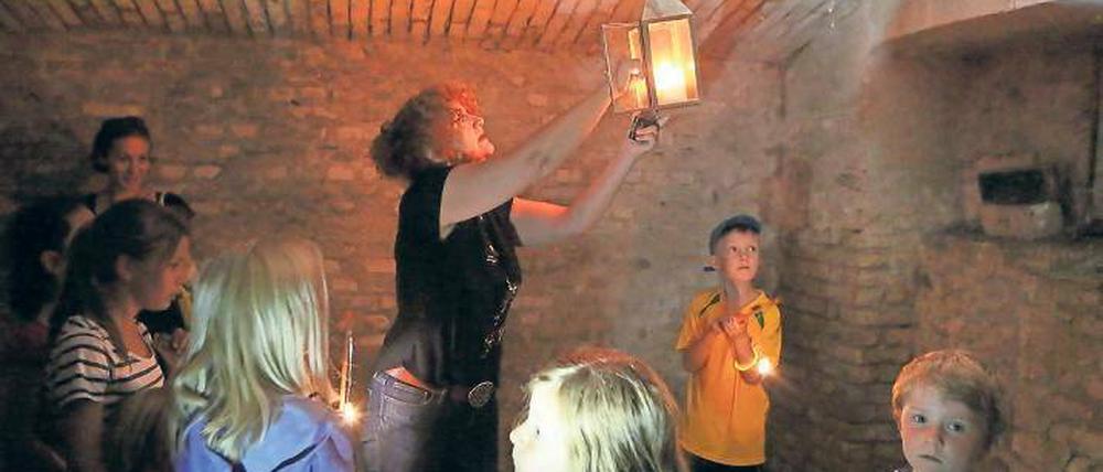 Kerzenlicht im Keller. Welche Schätze sie im Hofgärtnerhaus einst barg, zeigt Petra Wesch den Kindern beim Sommerfest. Am Sonntag wurde dazu noch Gold entdeckt.
