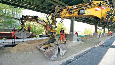 Zärtliches Baggern. Mit viel Gefühl wird der Sand über den Bahnsteig verteilt. Ab Freitag ist eine Seite wieder begehbar. Andreas Krause überwacht die Arbeiten. Auch die Stützmauern des Dammes werden erneuert, die Geschäfte im Bahnhof sind geöffnet.