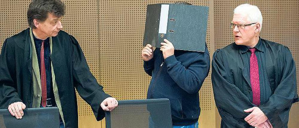 Kein Mörder. Mit einem Aktenordner vor seinem Gesicht steht der Angeklagte Michael Bernd D. bei seinem Anwalt.